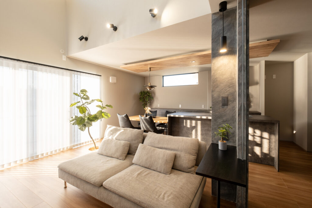 大きな掃き出し窓から自然光が差し込む、木の床とグレートーンでまとめられた開放的なLDK空間