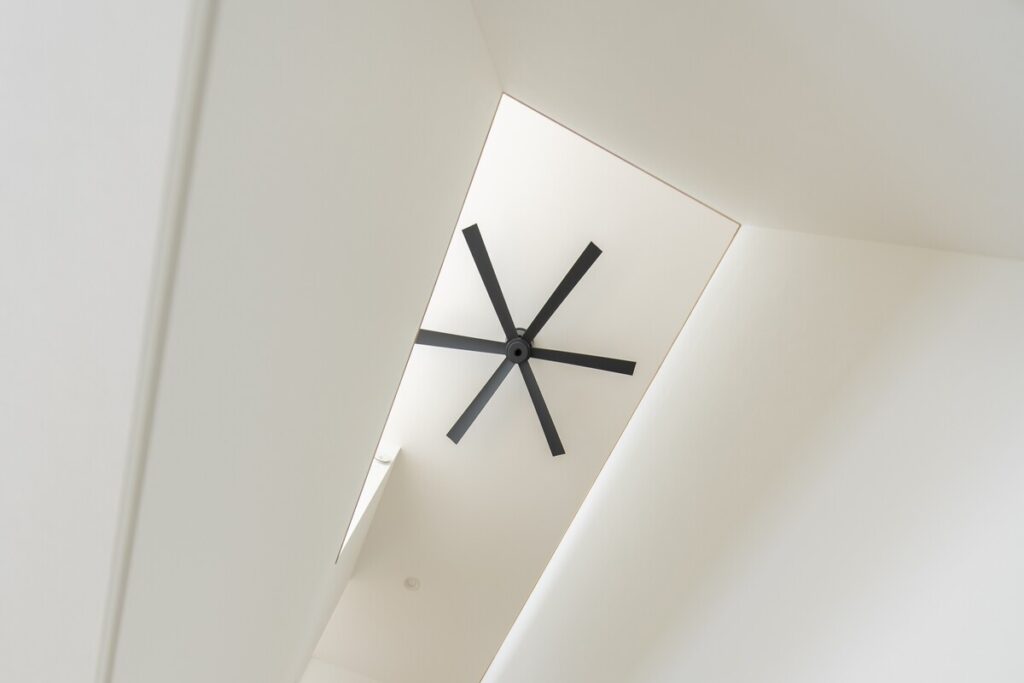 吹き抜け天井に設けられたトップライトと、シンプルなデザインのシーリングファン