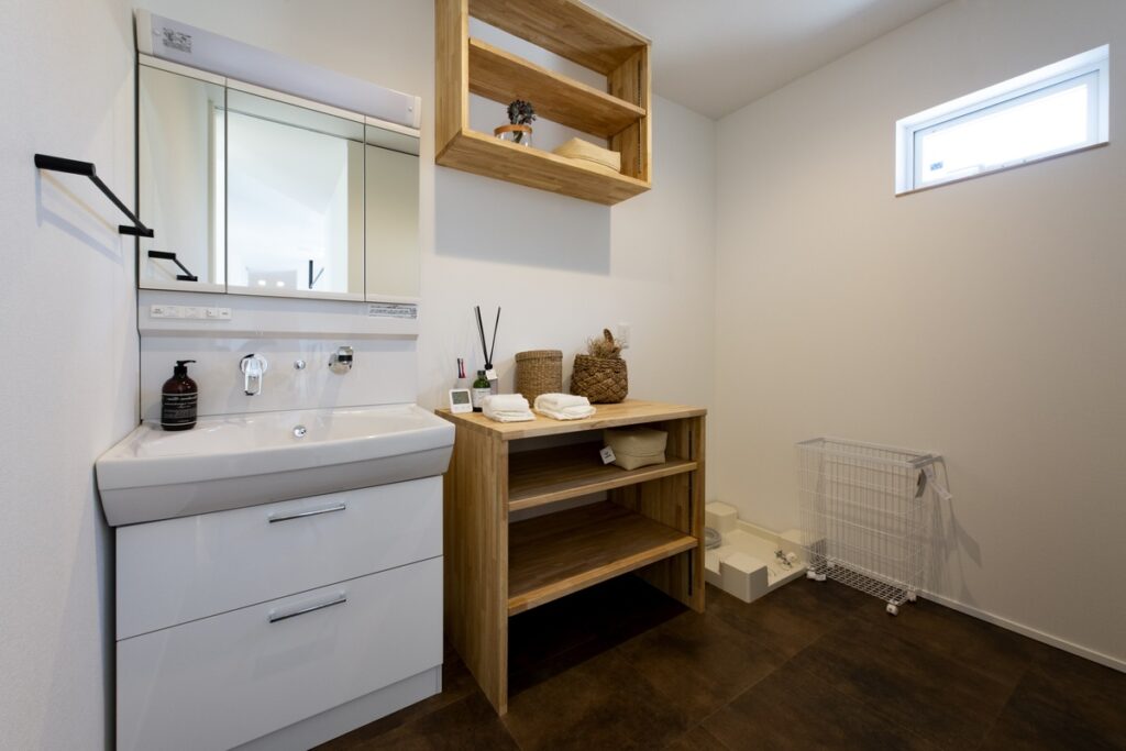 洗面台と木製オープン棚を備えた、明るく清潔感のある洗面脱衣室
