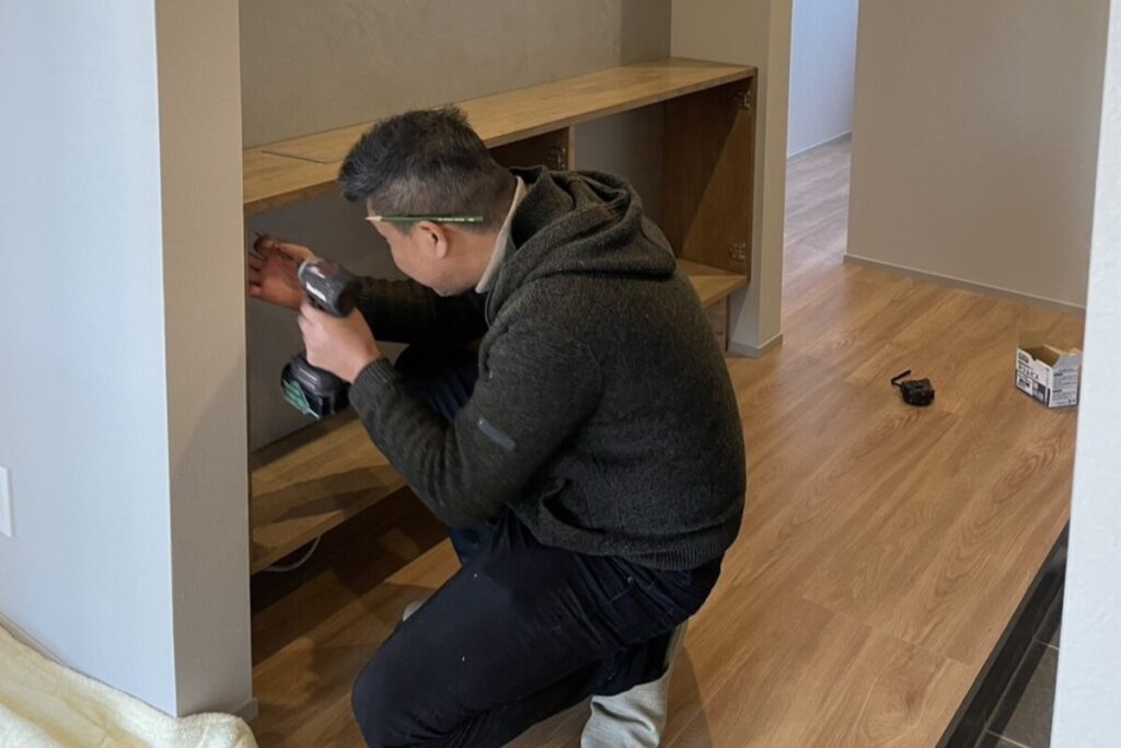 造作収納の内部で、電動ドライバーを使い丁寧に施工作業を行っている様子