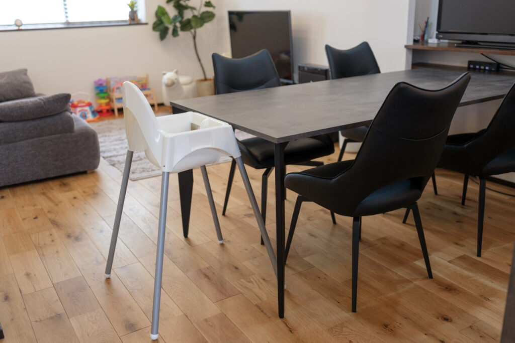 ダイニングテーブルとチェアの横にベビーチェアが配置された、リビングと一体になった食事空間