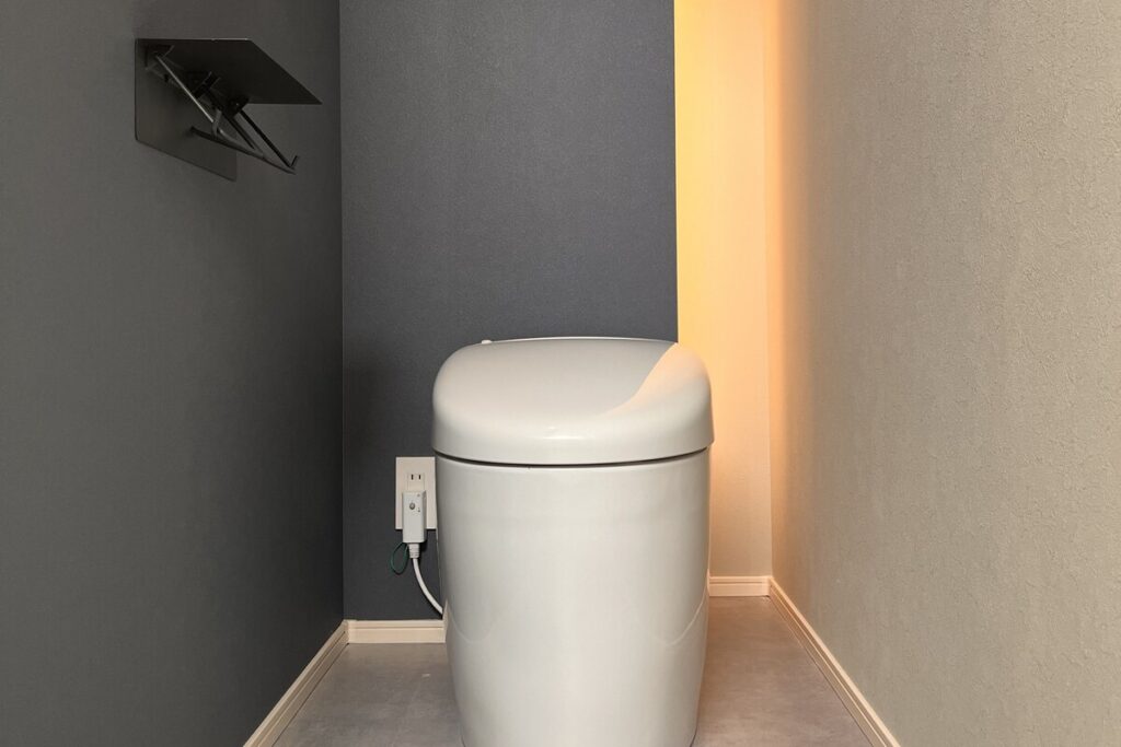 間接照明により落ち着いた雰囲気に整えられた、ミニマルなデザインのトイレ空間