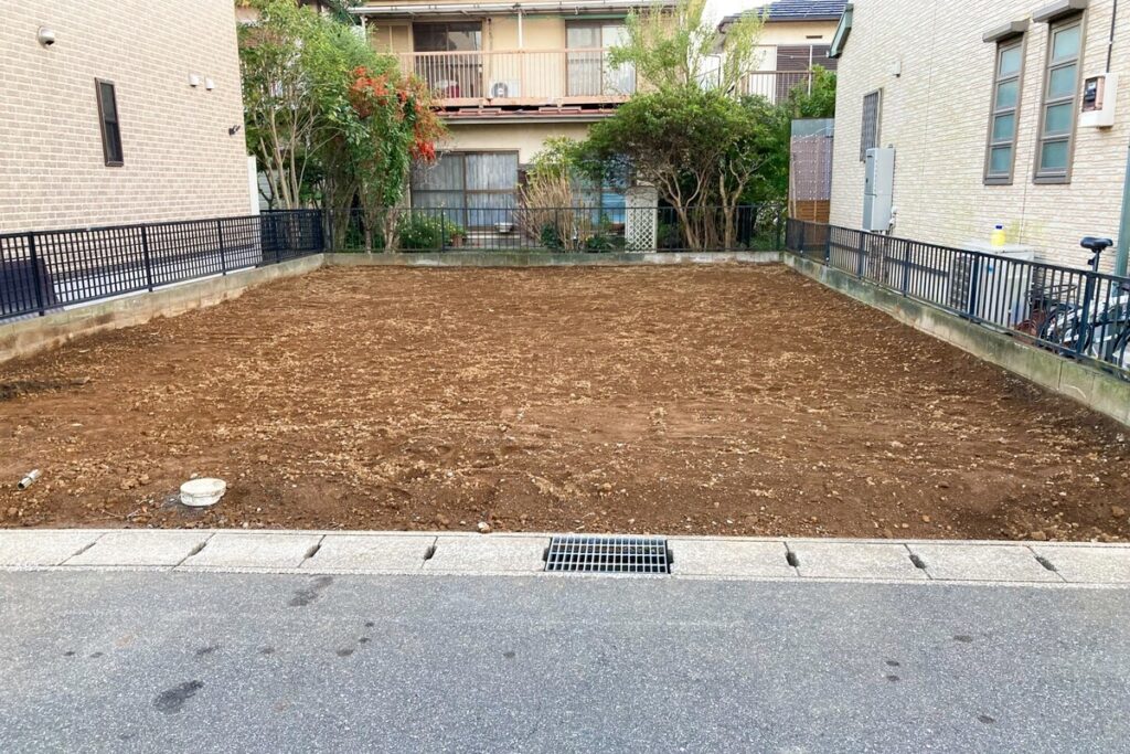 周囲をフェンスで囲まれ、住宅の建築に向けて綺麗に整地された、日当たりの良い平坦な分譲地の更地。