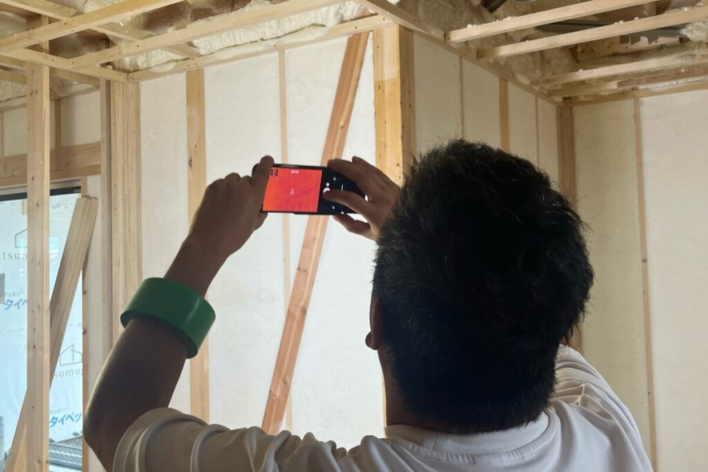 施工中の現場にてサーモグラフィー診断を行い、断熱材が隙間なく充填されているか施工品質を確認する様子。