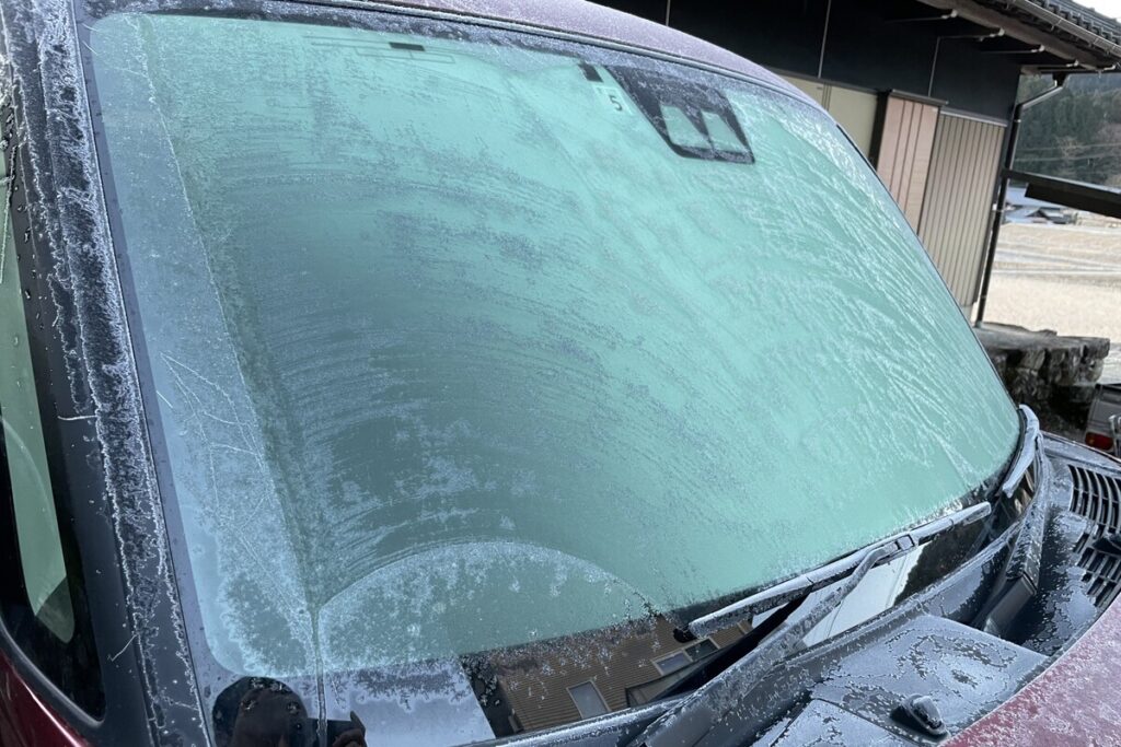 厳しい寒さにより、屋外駐車でフロントガラスに放射冷却による霜がびっしりと降りてしまった凍結状態の車両。