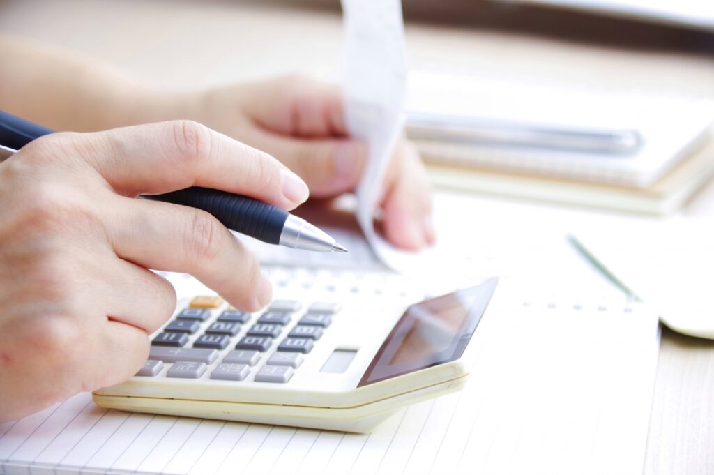 住宅購入の資金計画を立てる際、電卓や家計簿を使って詳細な予算シミュレーションを行っている手元のクローズアップ。