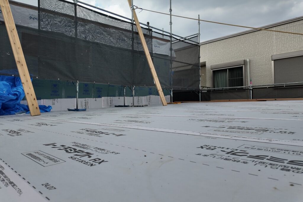 屋根の長期的な防水性能を確保するため、透湿防水ルーフィングシートが隙間なく丁寧に施工された建築中の住宅。