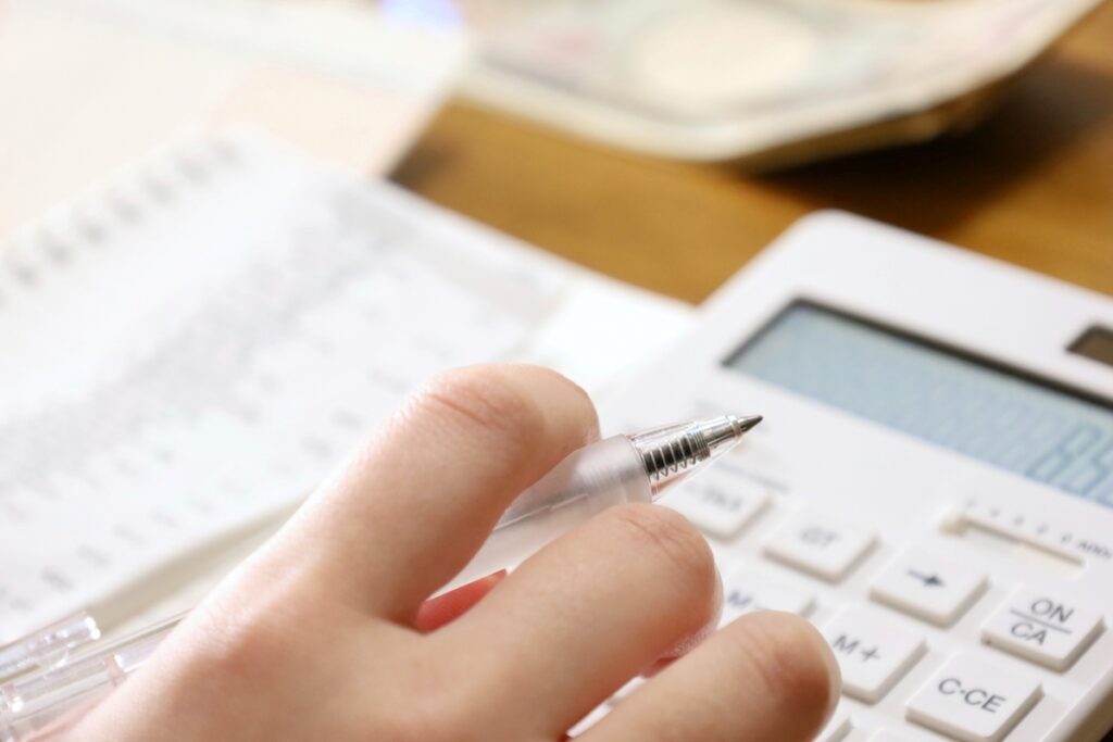 電卓とペンを使い、通帳や家計簿を確認しながら進める家づくりの資金シミュレーション。将来のメンテナンス費用まで見据えた計画的な検討。