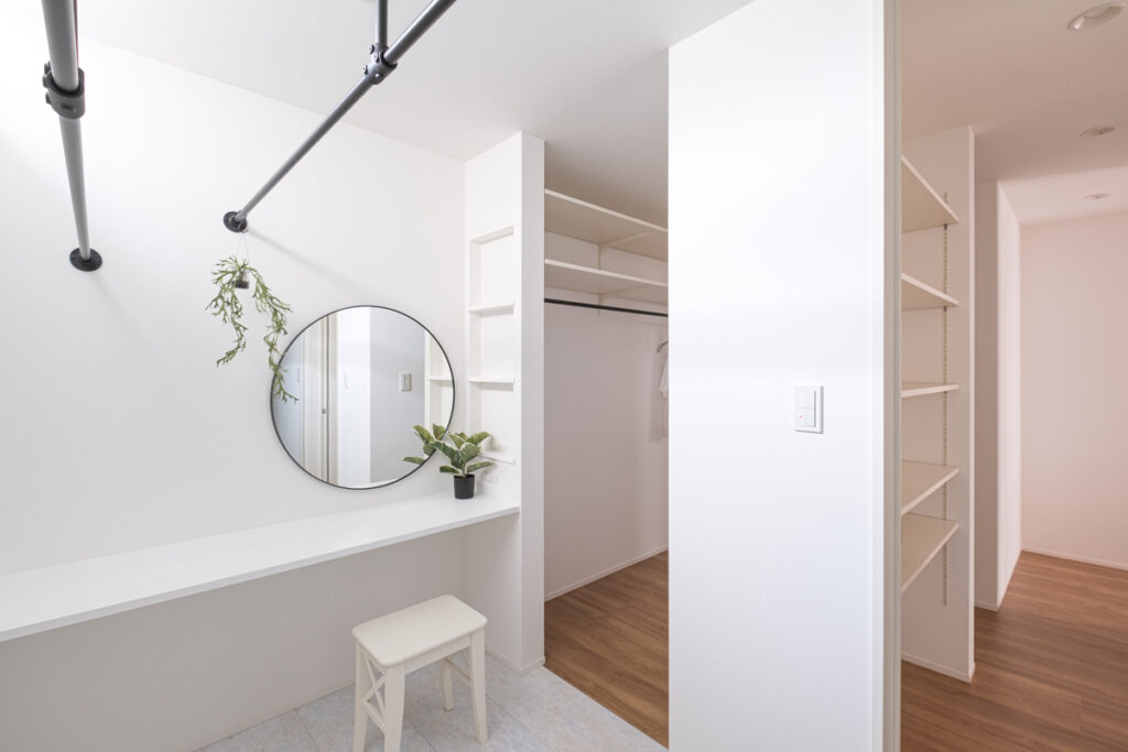 白を基調とした清潔感のあるパウダールーム。丸い鏡と黒のハンガーパイプを設えた、室内干しも可能な機能的でデザイン性の高い家事スペース。